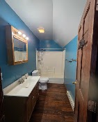 Remodeled bathroom with blue walls, a wood vanity, and dark wood flooring by T & A Contracting