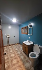 Remodeled bathroom with blue walls, wood vanity, and framed mirror by T & A Contracting
