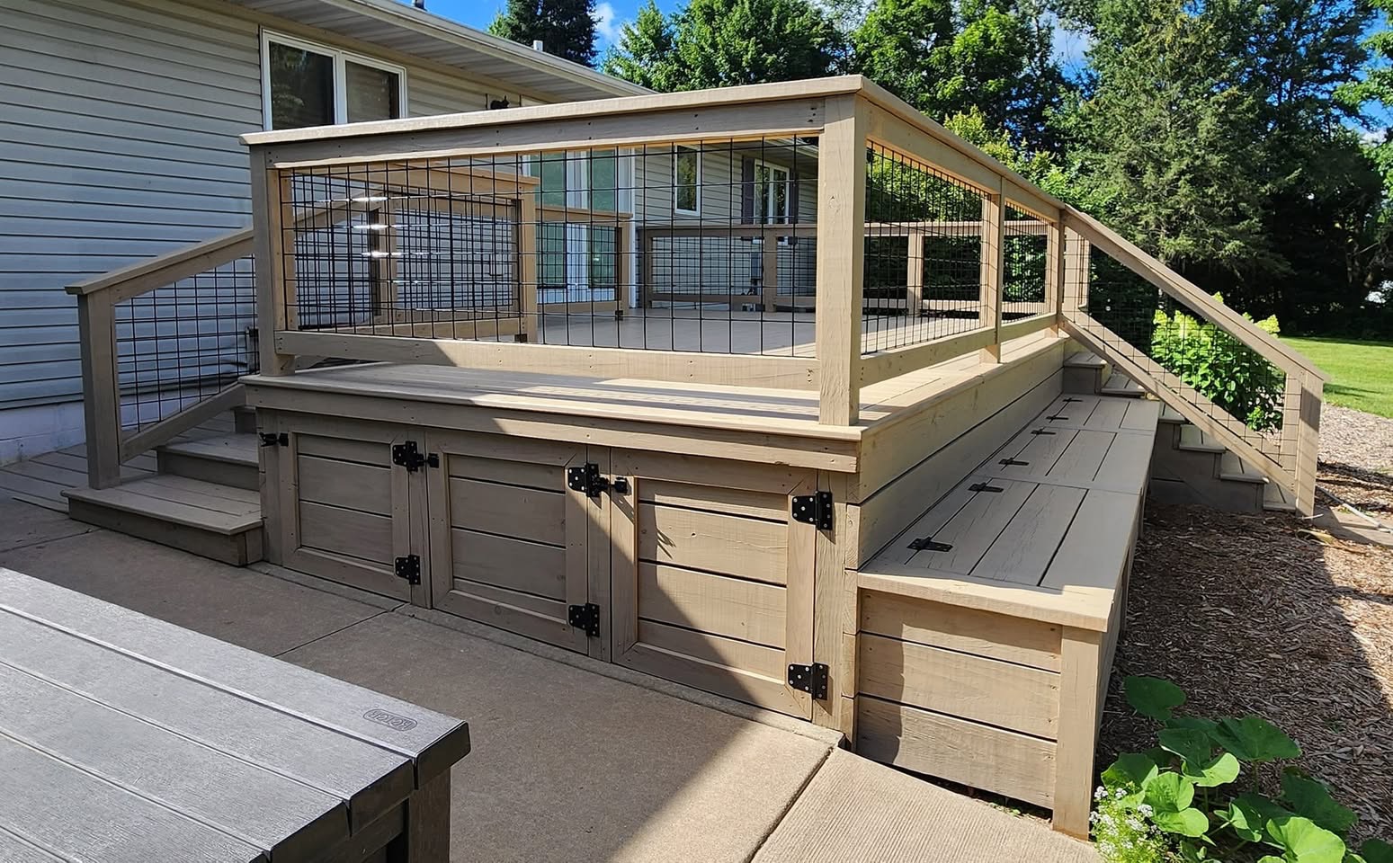 Natural wood deck with hog-wire railings and built-in storage benches built by T & A Contracting