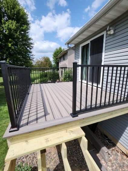 Gray composite deck with black aluminum railings on the back of a home by T & A Contracting