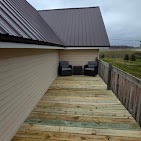 New pressure-treated deck with black railings and rural views, rebuilt by T & A Contracting
