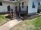 New deck with black railing, steps, and a paver walkway by T & A Contracting