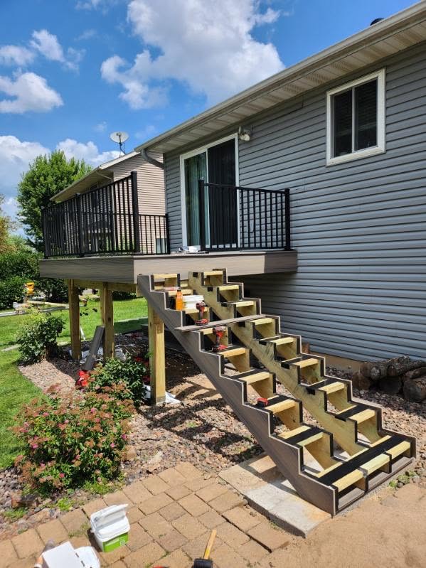 Raised deck with black railings and stair stringers under construction by T & A Contracting