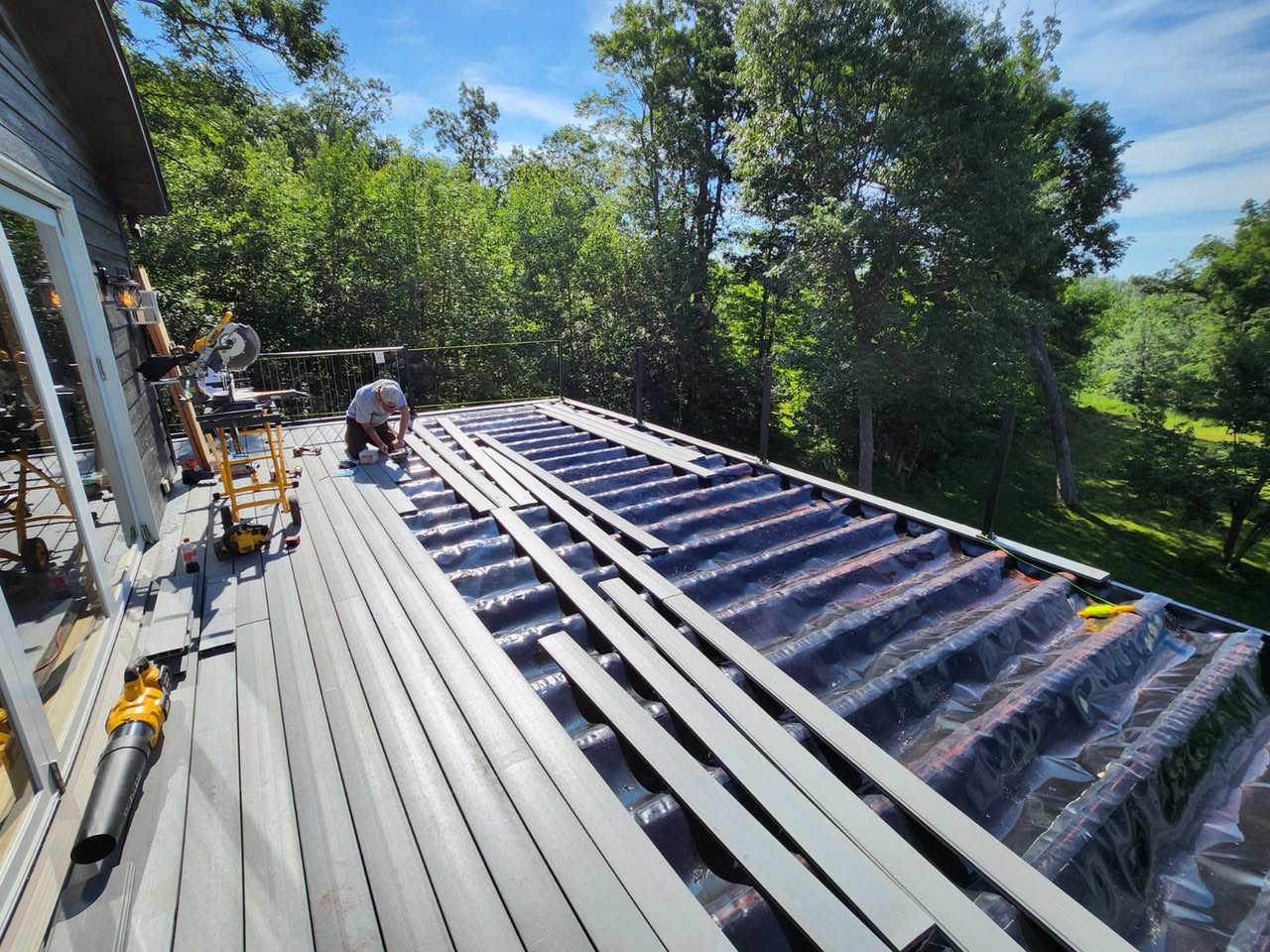 Craftsman installing composite deck boards over a framed and waterproofed deck structure for T & A Contracting