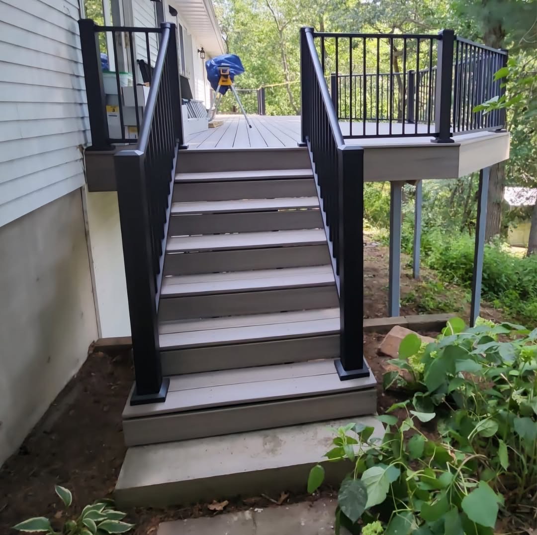 Wide composite deck stairs with black aluminum railings by T & A Contracting