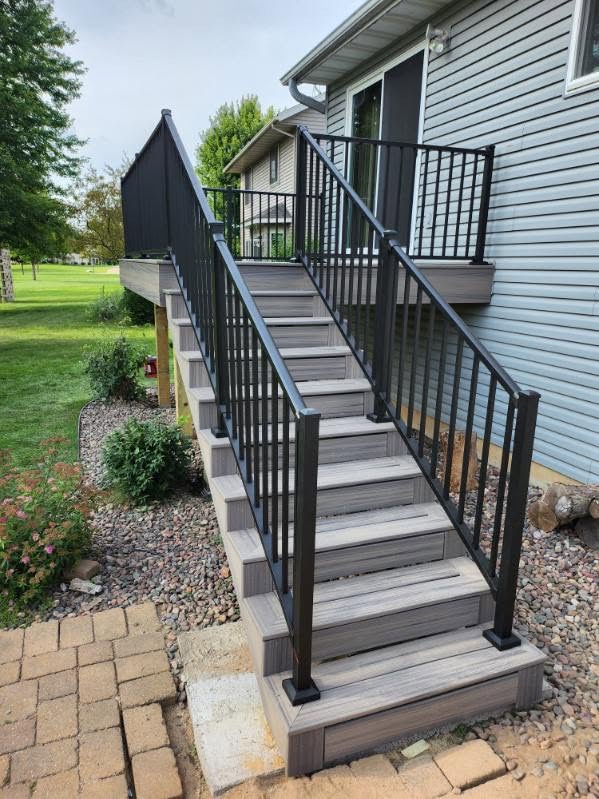 Gray composite deck staircase with black aluminum railings by T & A Contracting