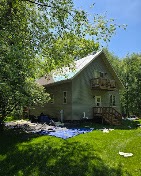 Two-story wooded cabin being stained green with full prep and masking by T & A Contracting