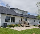White home with a new dark shingle roof and patio by T & A Contracting