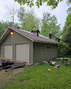 Crew installing new shingles on a detached garage roof by T & A Contracting