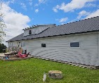 White-sided home with a new gray shingle roof by T & A Contracting
