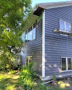 Two-story home with new gray-blue siding partially installed by T & A Contracting