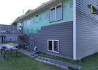 Home being resided with gray siding and a new white door over an old green exterior by T & A Contracting