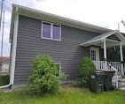 Raised-entry home with gray lap siding and a white porch by T & A Contracting