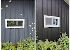 White-trim windows in deep black board-and-batten siding installed by T & A Contracting